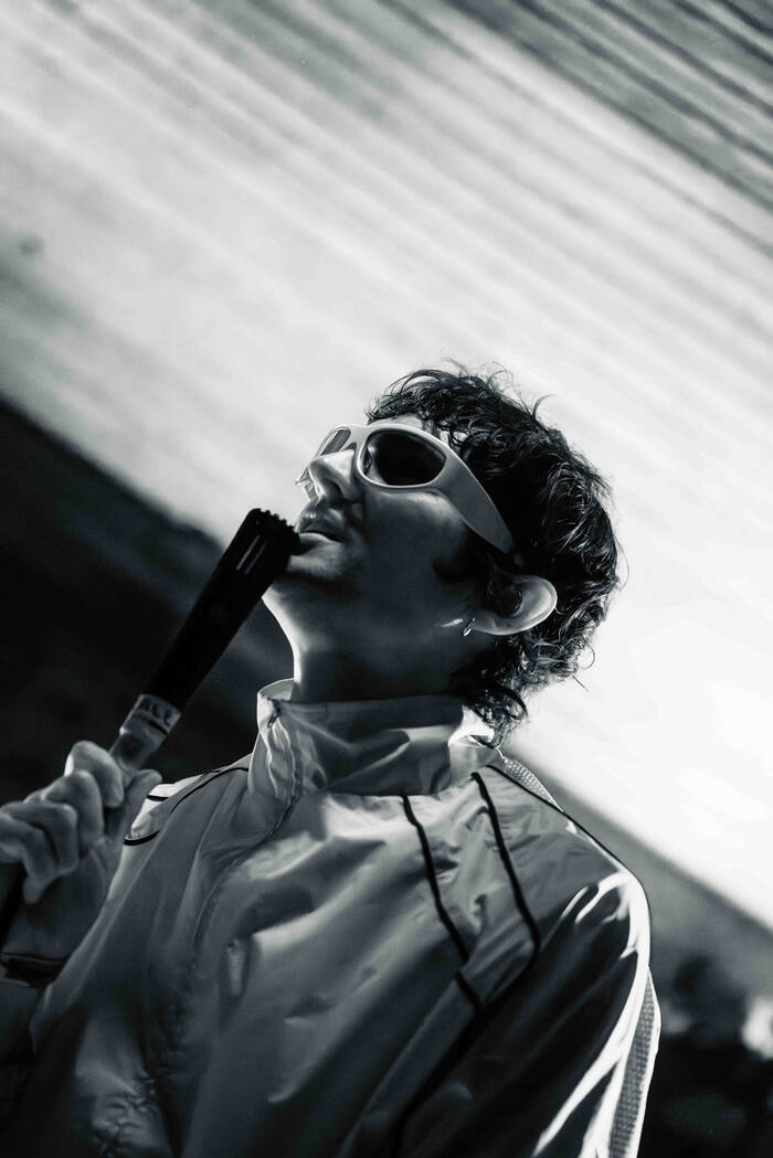 Black and white photo of a performer tilting their head back while singing into a handheld mic
